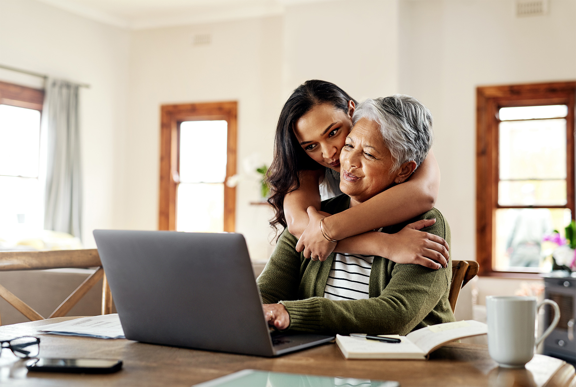 Elderly person with daughter smiling at laptop in home