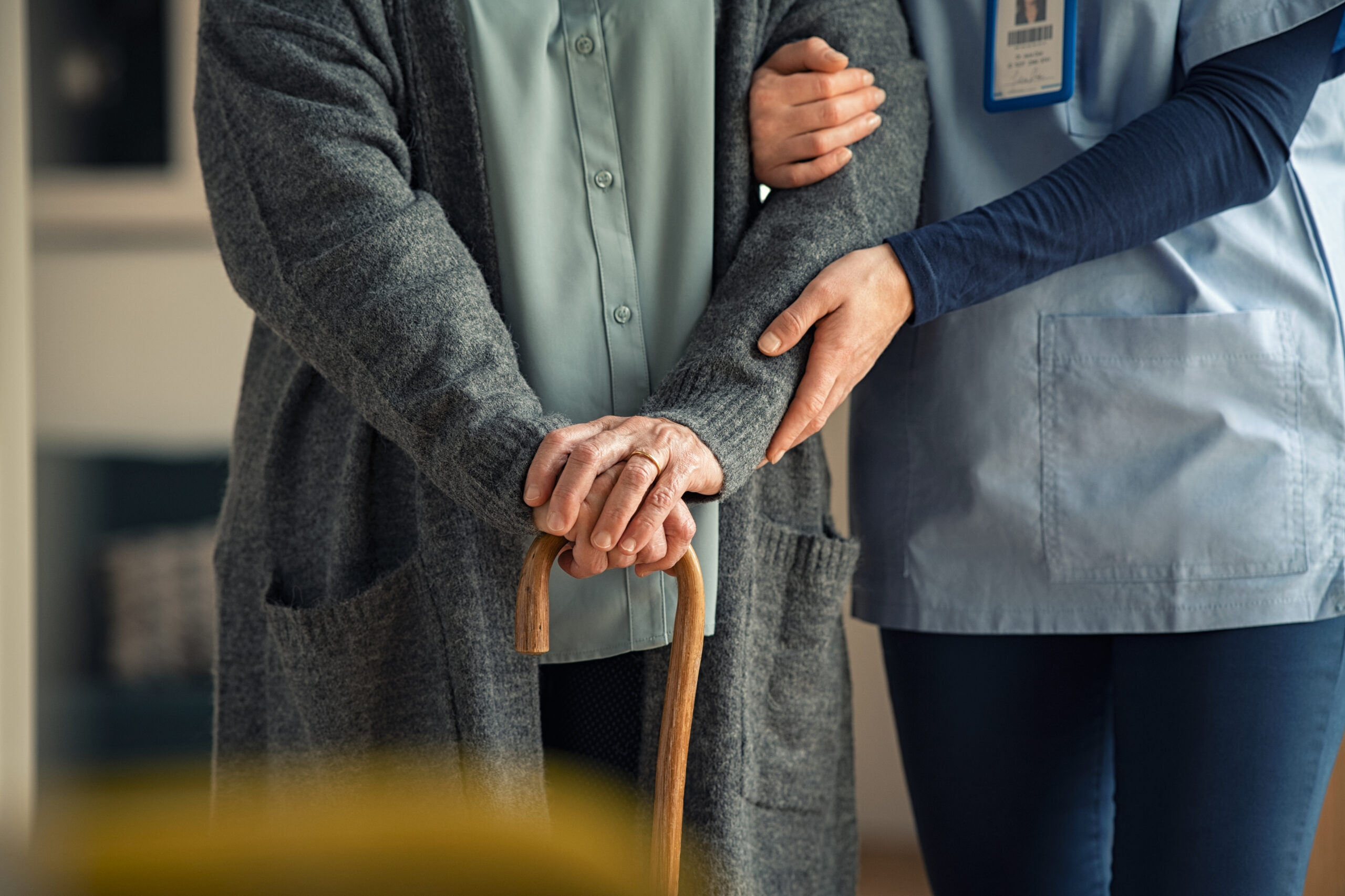 Nurse helping older woman with cane
