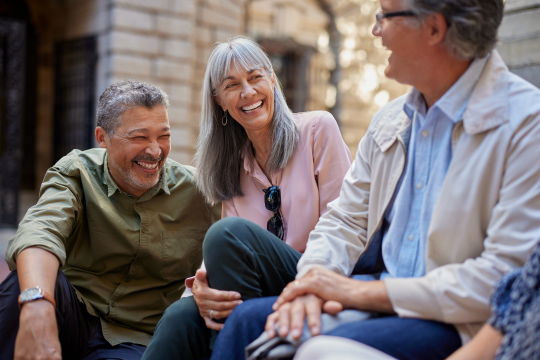 A diverse group of older adults having a conversation outdoors.